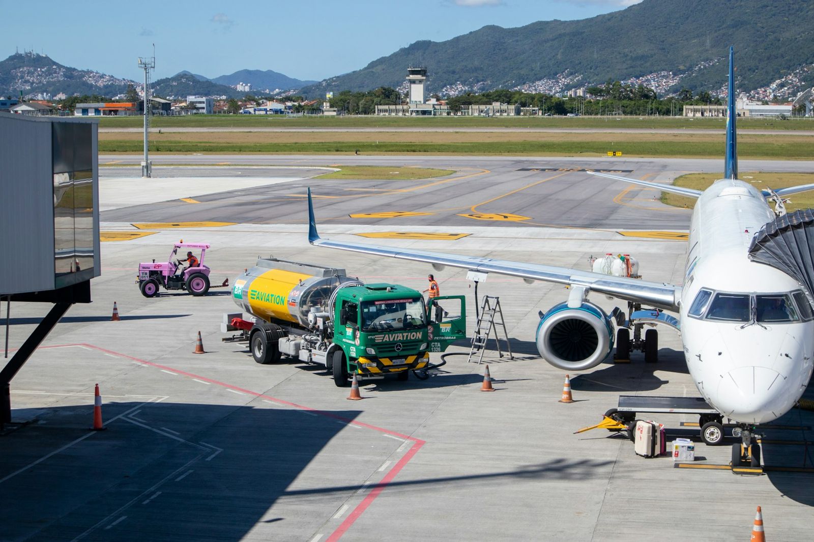 Camion avitailleur garé sous l'aile d'un avion, montagnes en arrière-plan
